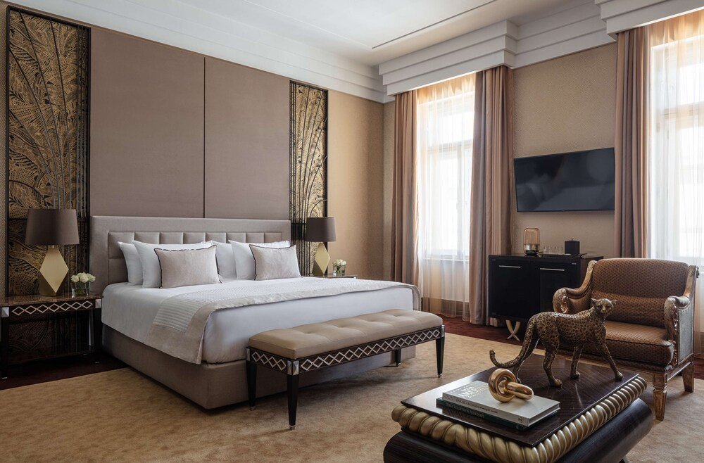 Spacious bedroom with a bench and a sofa in a palace suite