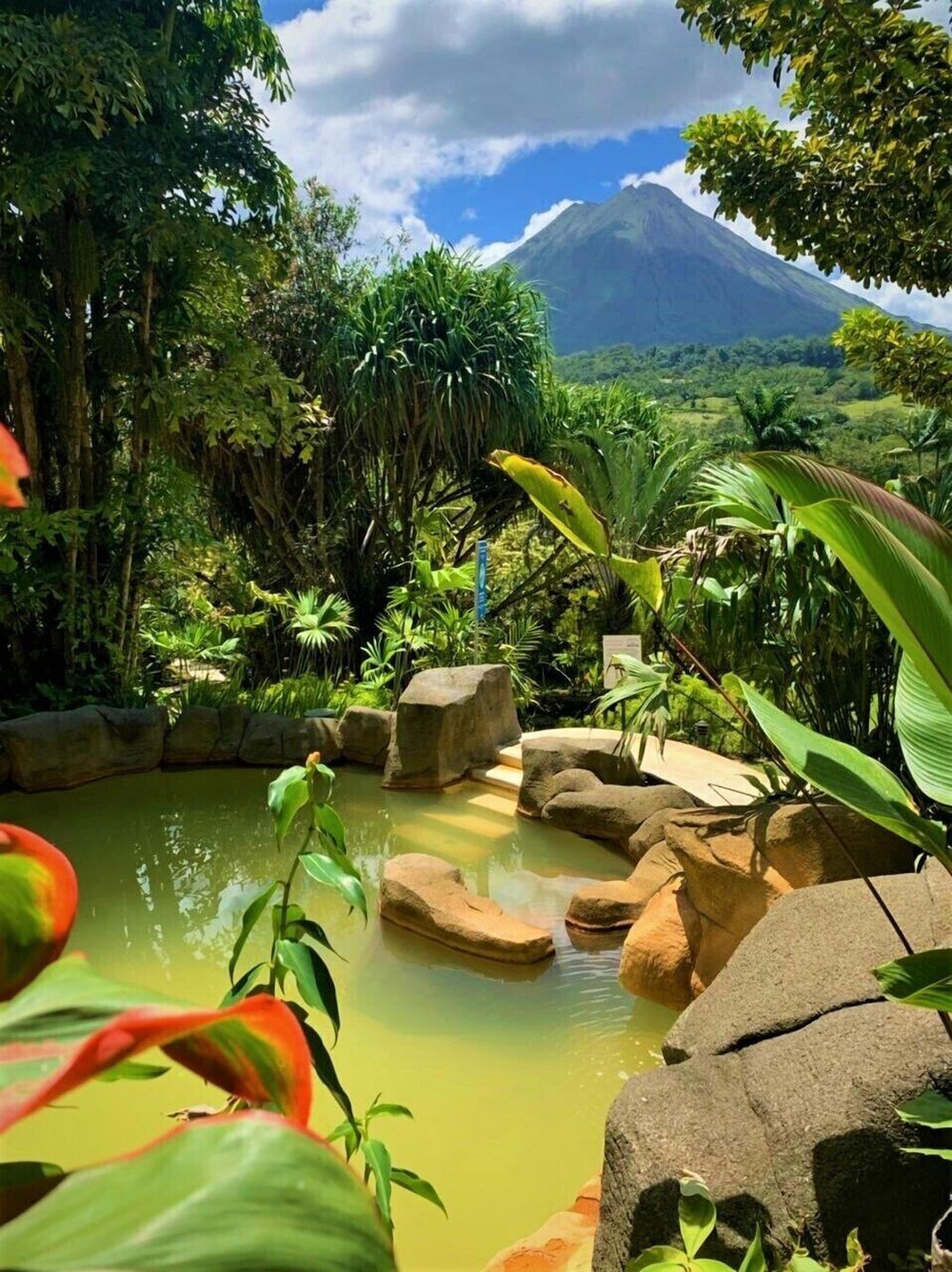 Natural landscape with a pond, rocks and lush greenery at Arenal Paraiso