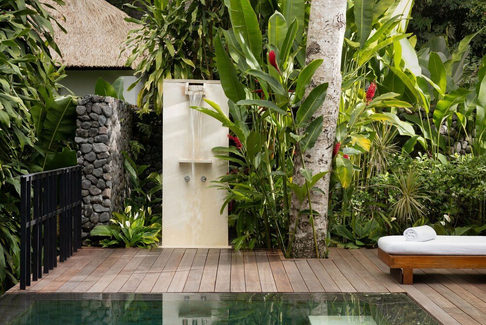 Private pool area with a wooden deck and a stone wall