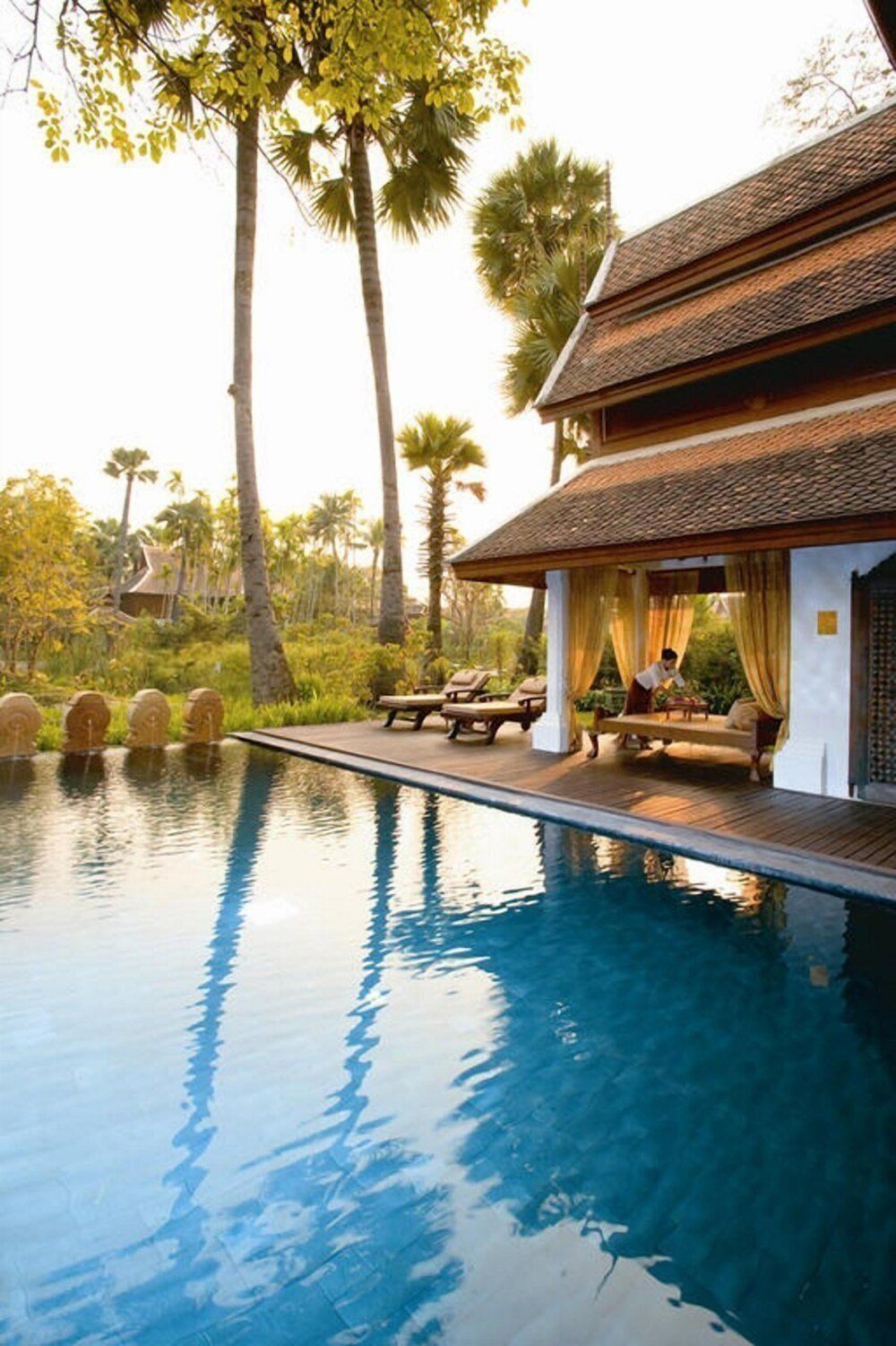 Resort swimming pool surrounded by landscaped grounds and loungers
