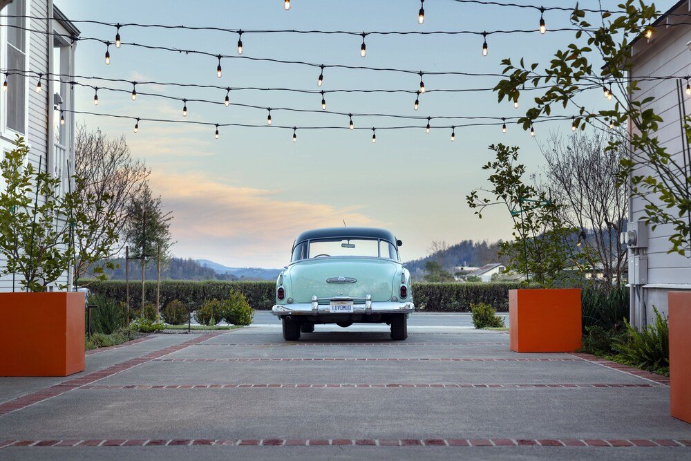 Vintage car parked in a driveway beneath string lights