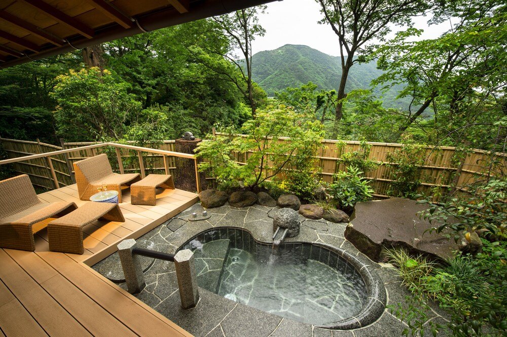 Jacuzzi rodeado de muebles de deck de madera y un camino de piedra