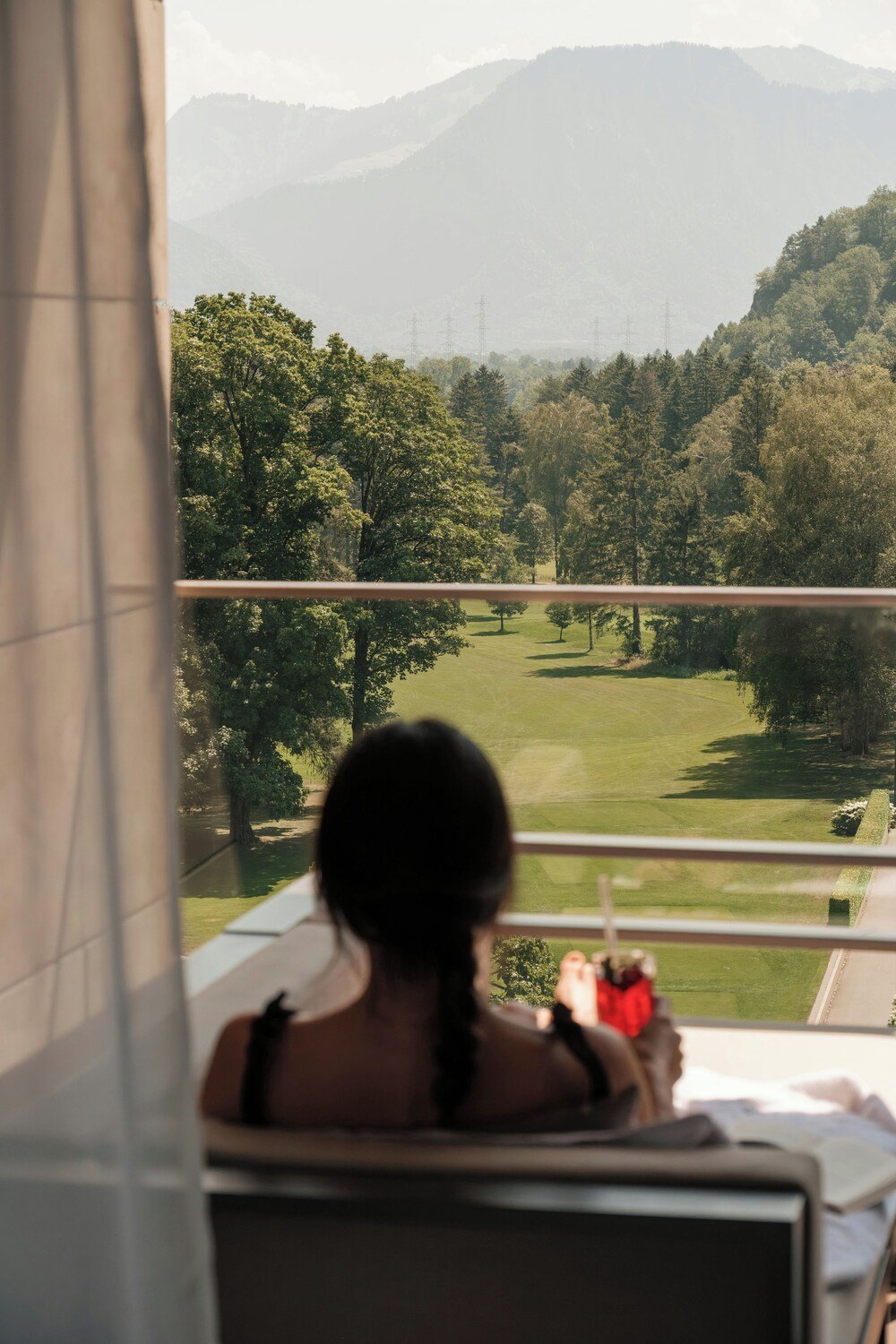 Persona sentada junto a una ventana con vista a un paisaje verde