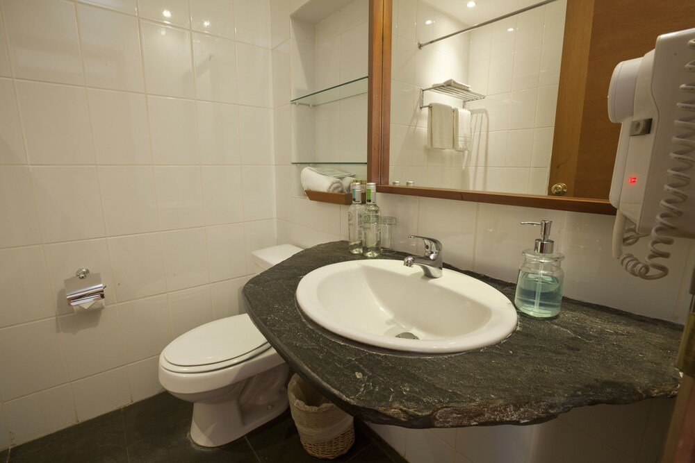 Baño con mesada de mármol y un espejo grande