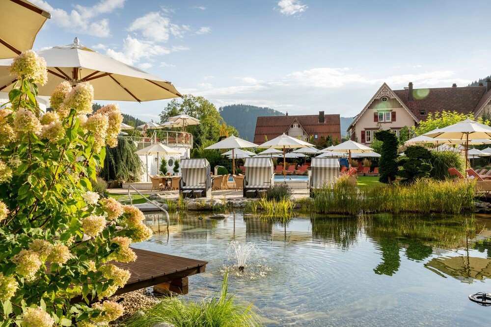 Escena junto al lago con mesas al aire libre bajo sombrillas