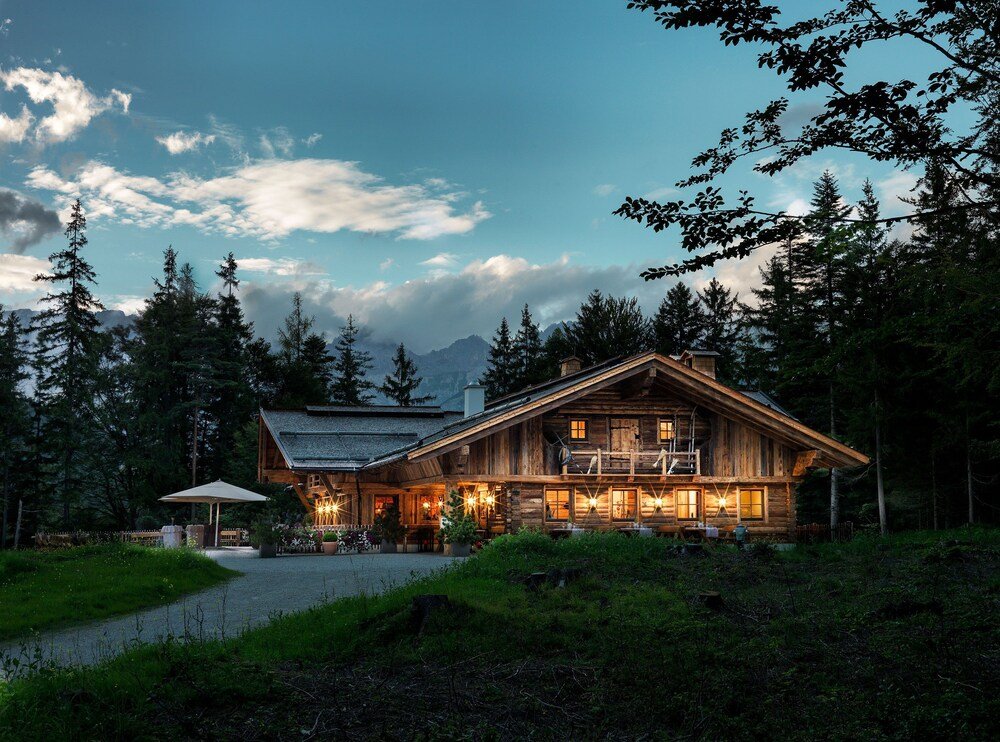 Edificio rústico de madera tipo chalet con balcón entre el bosque