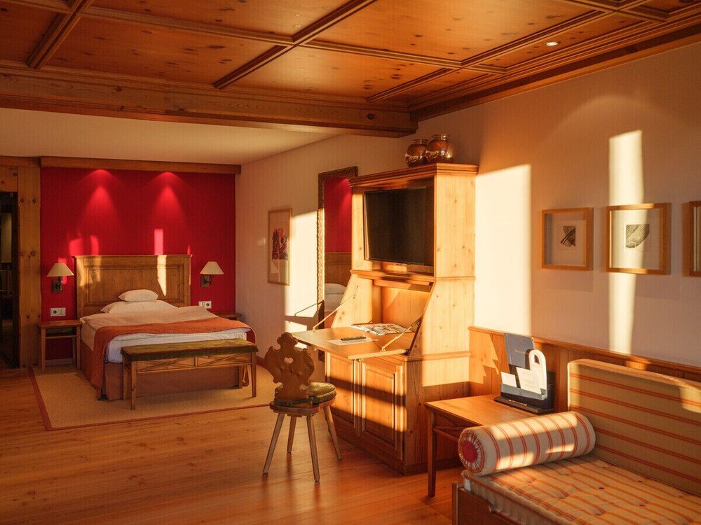 Habitación acogedora con cama de madera y escritorio en el hotel del Tirol