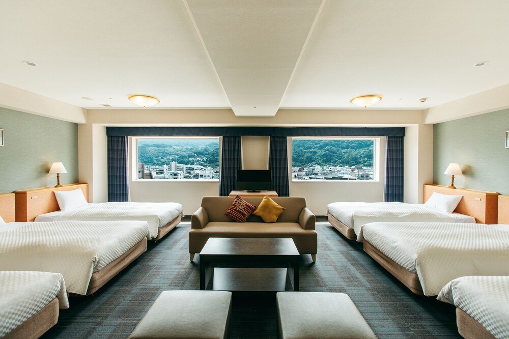 Habitación del hotel con dos camas y un sofá en Beppu