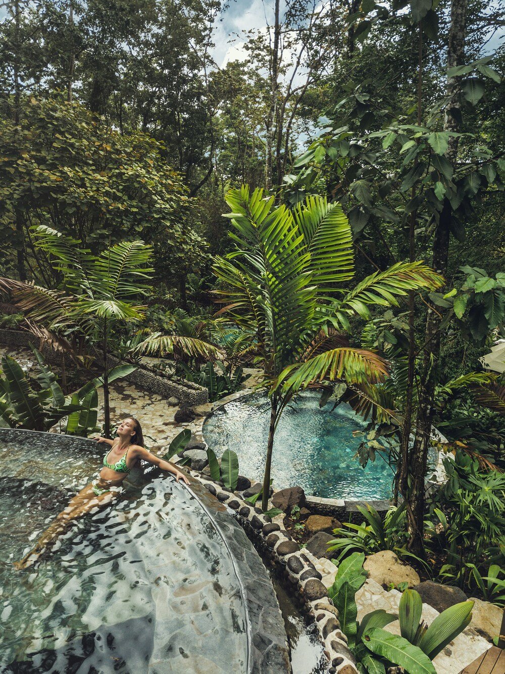 Woman relaxing in a pool with a transparent water slide at the resort