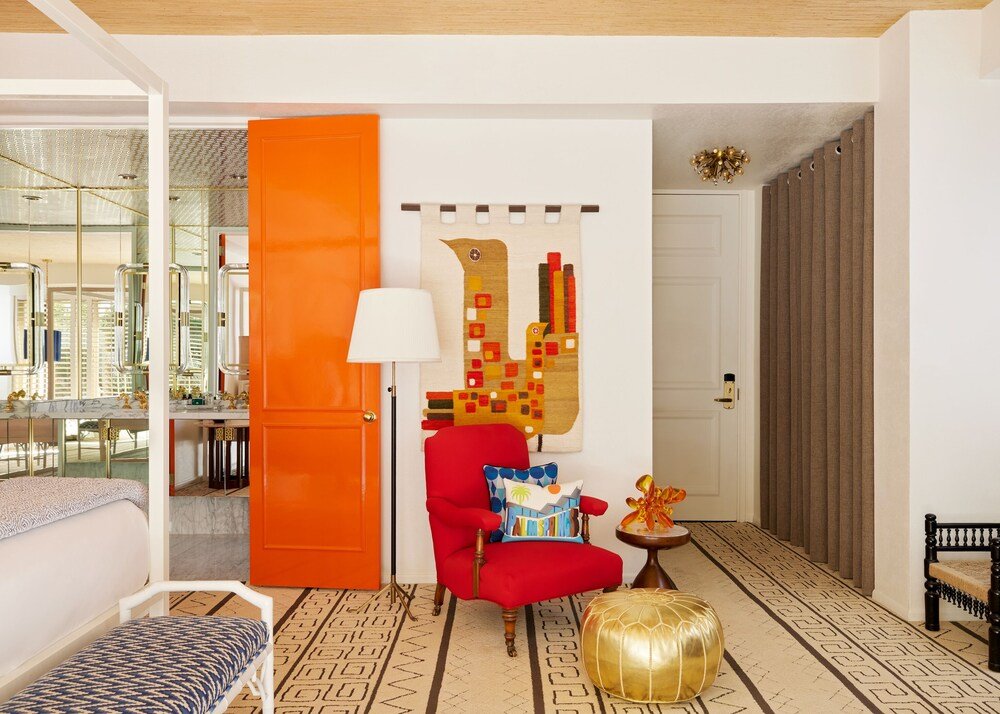 Habitación del hotel con una gran puerta naranja y decoración vivaz