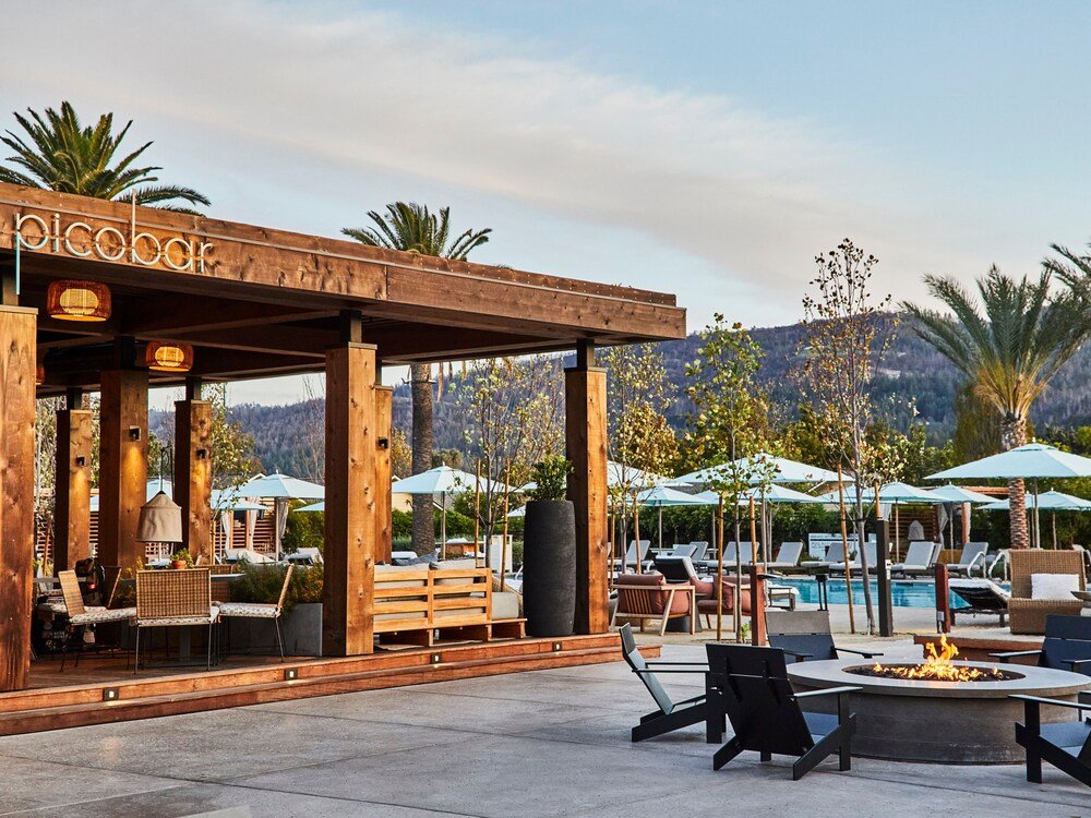 Wooden outdoor seating area with a fire pit among the gardens