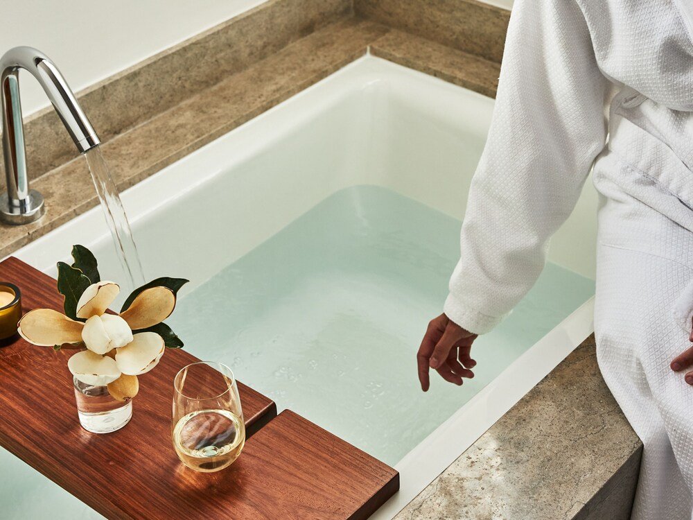 Bañera con una bandeja de madera en un baño del hotel