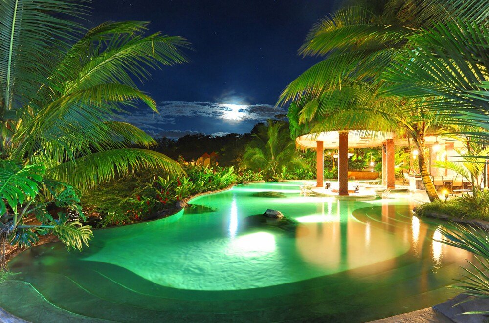 Nighttime pool area with palm trees and a lit gazebo