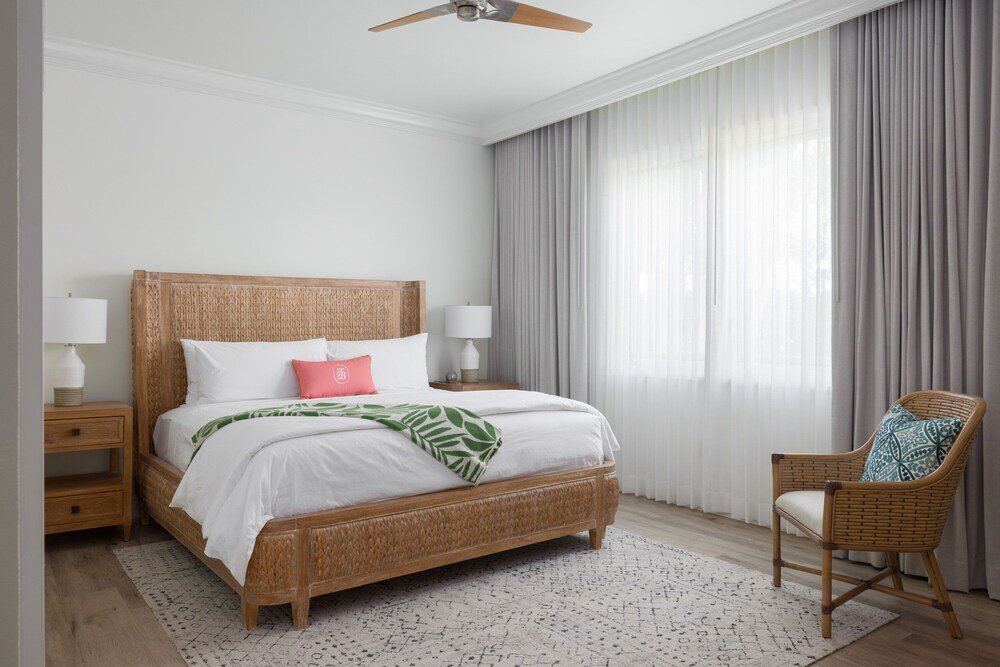 Dormitorio con una cama grande y una silla de mimbre